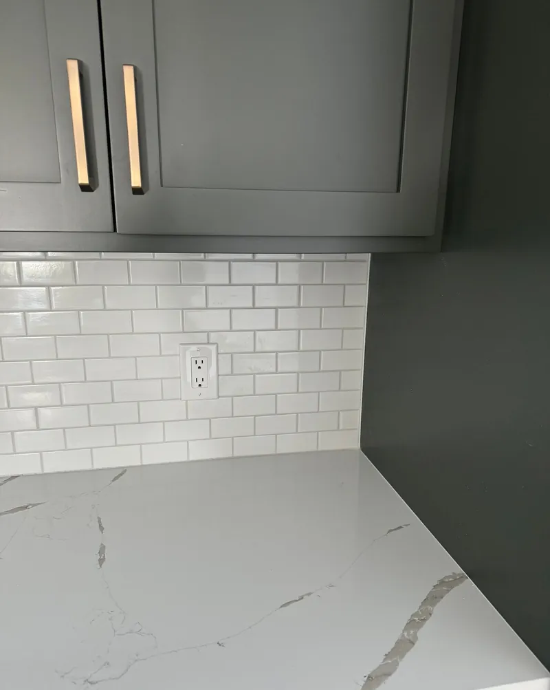 Running bond: white subway tile offset by half a tile, under dark cabinets.